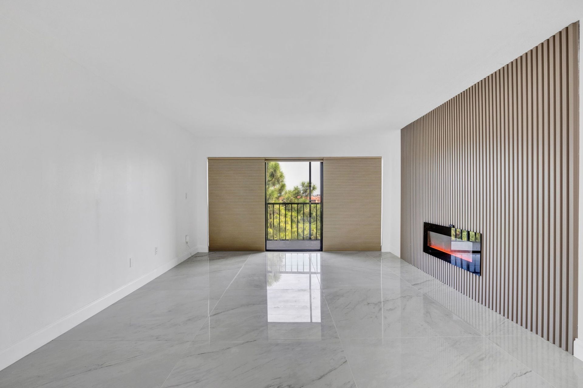 Empty white room with glossy floor, striped accent wall, and open doors to a balcony.