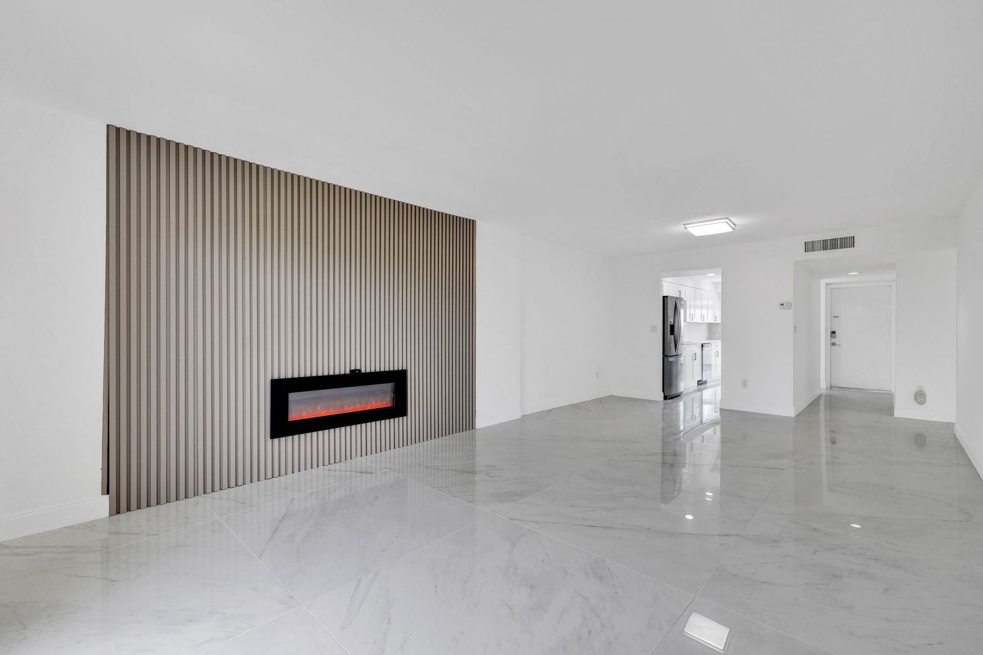 Minimal modern living room with white tile floor, vertical wood accent wall, and wall-mounted fireplace