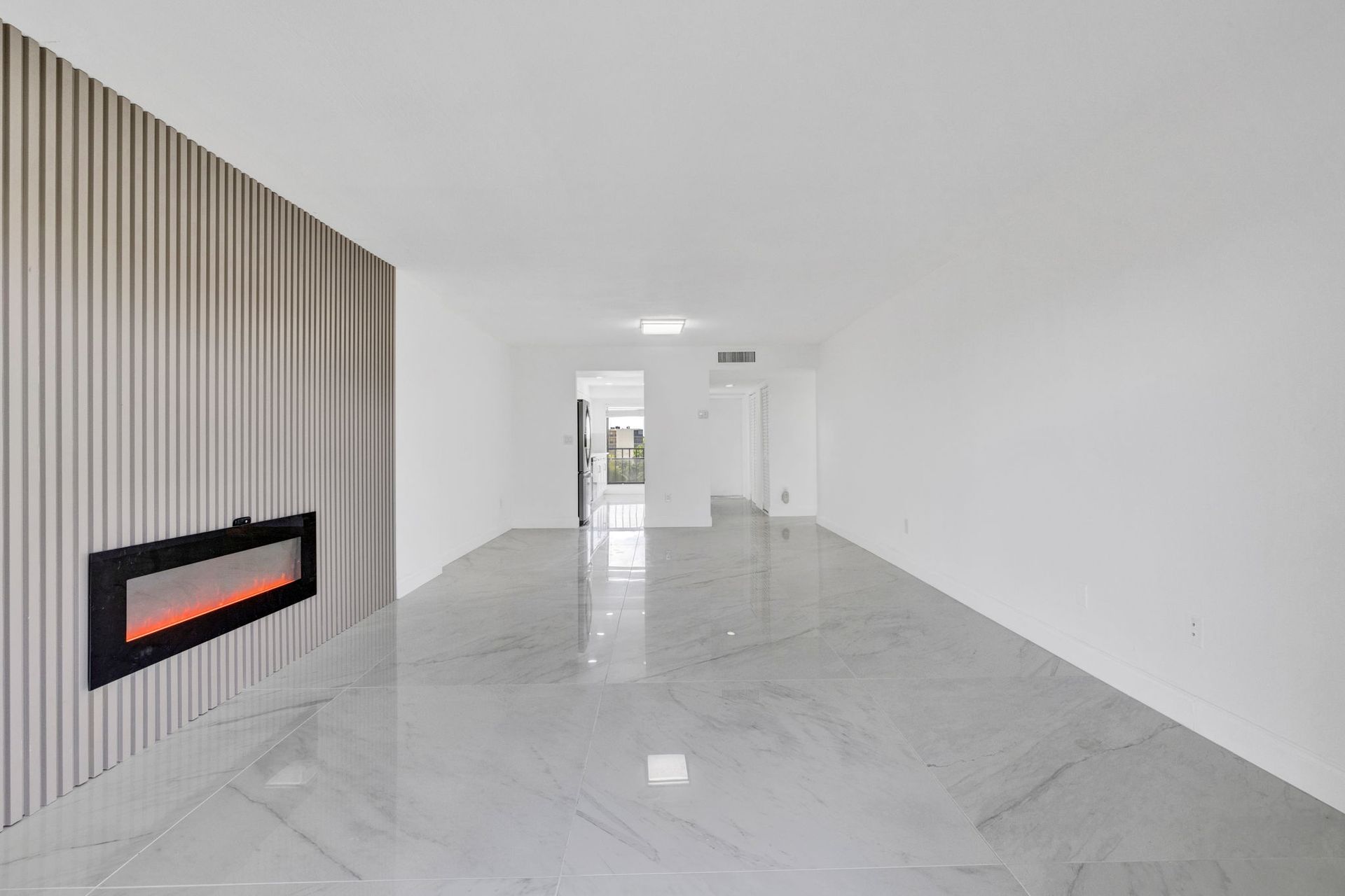 Empty modern living room with marble floor, white walls, and a built-in fireplace on the left.