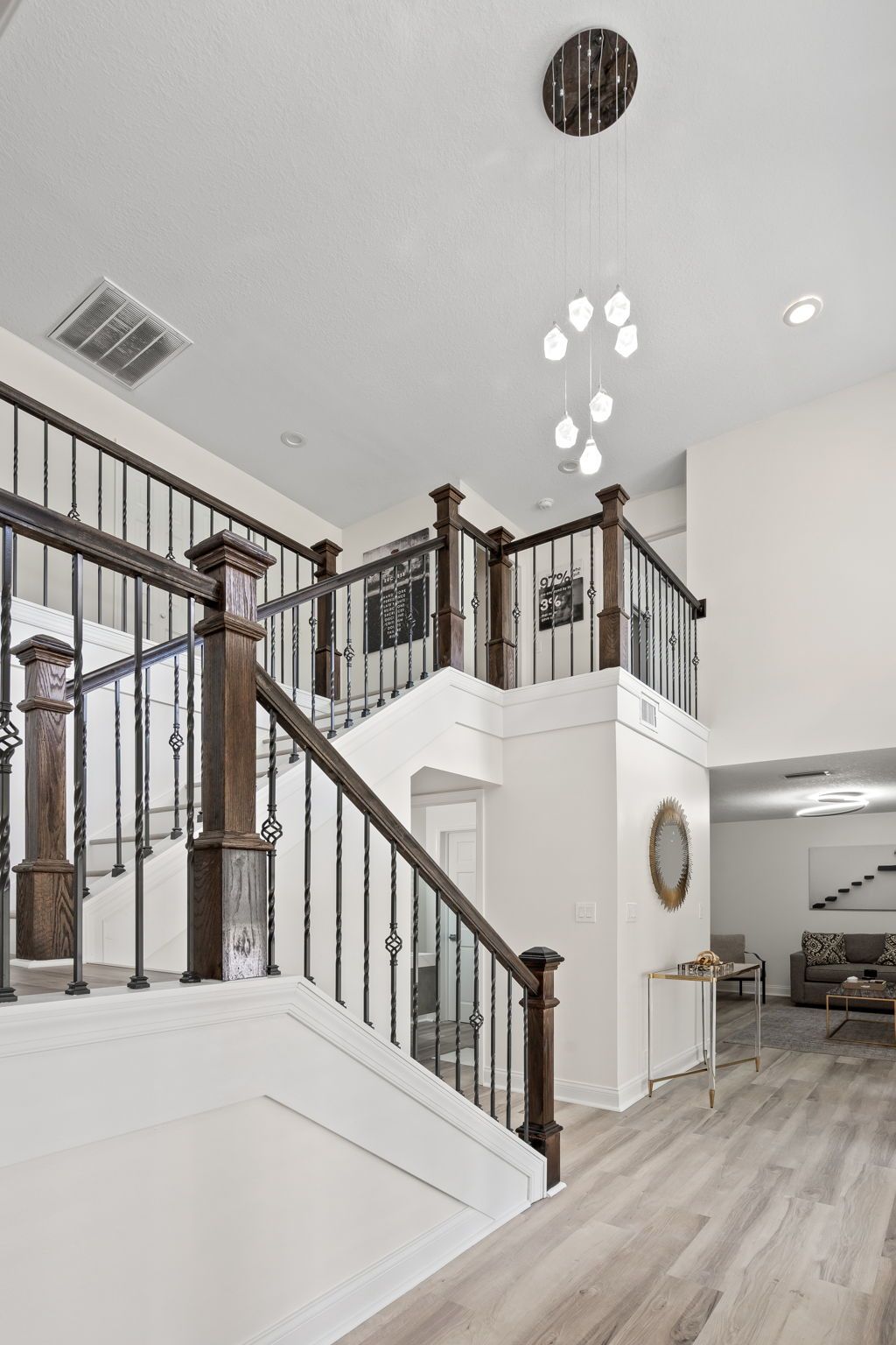 Modern foyer with white walls, dark wood staircase railings, and light wood flooring