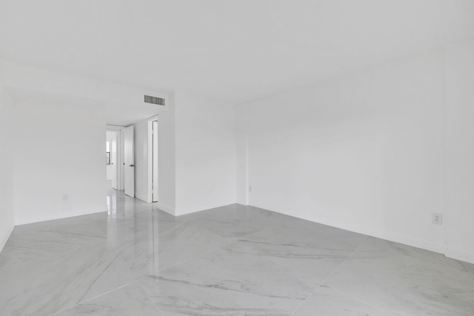 Empty white room with glossy marble floor and doorway in the back left.