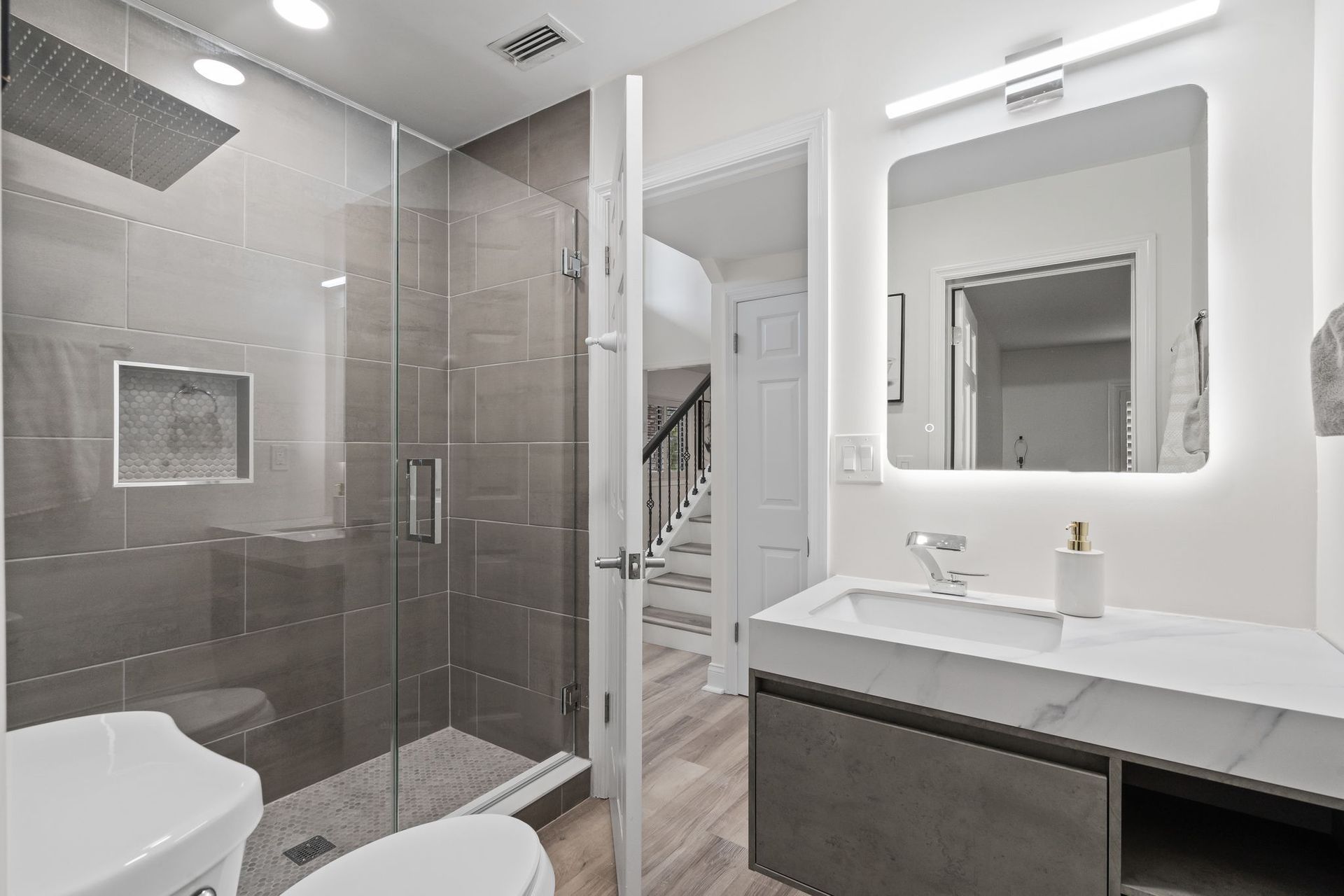 Modern bathroom with glass shower, white tile, and vanity with large mirror