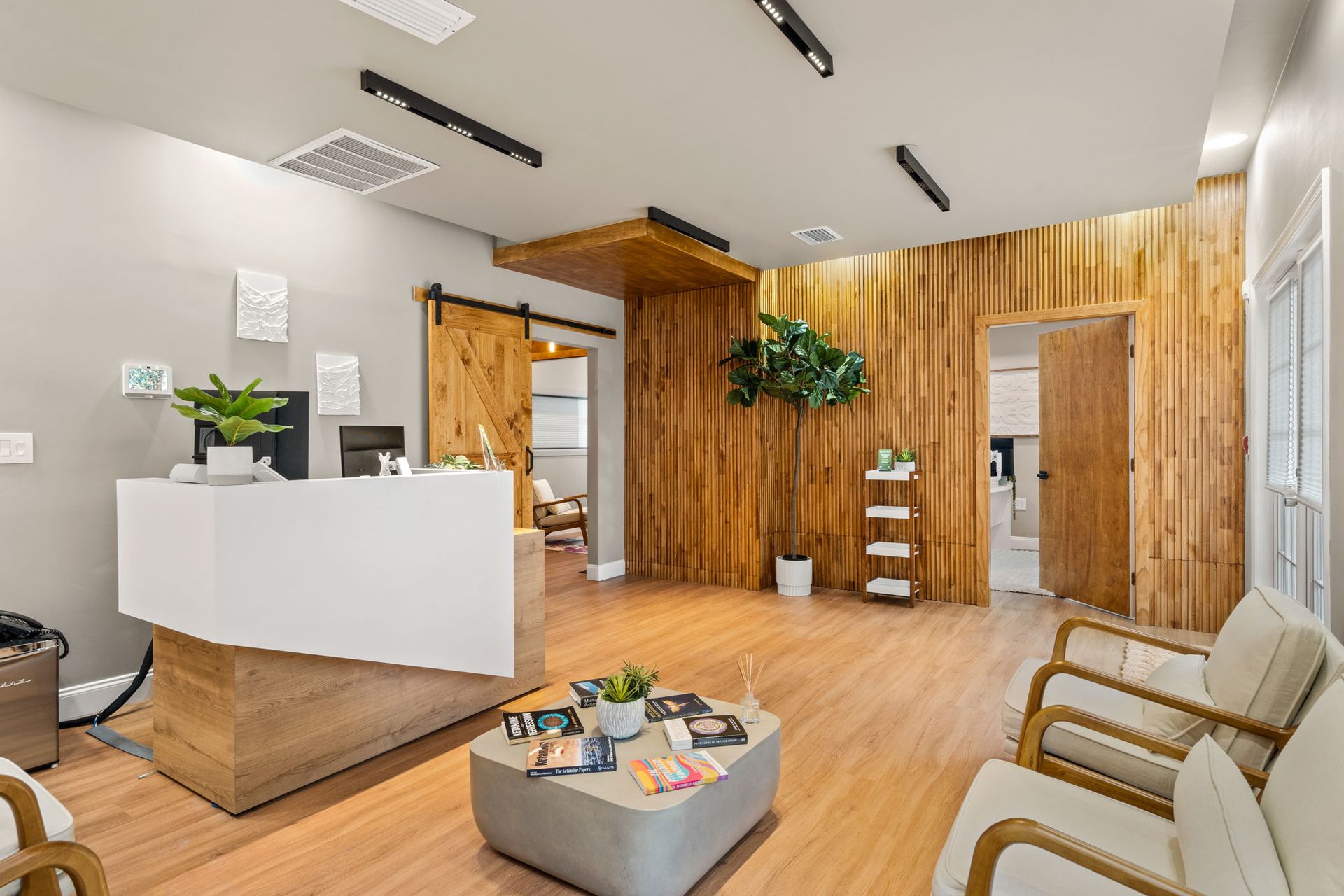 Modern reception area with wood-paneled walls, white front desk, lounge chairs, and coffee table
