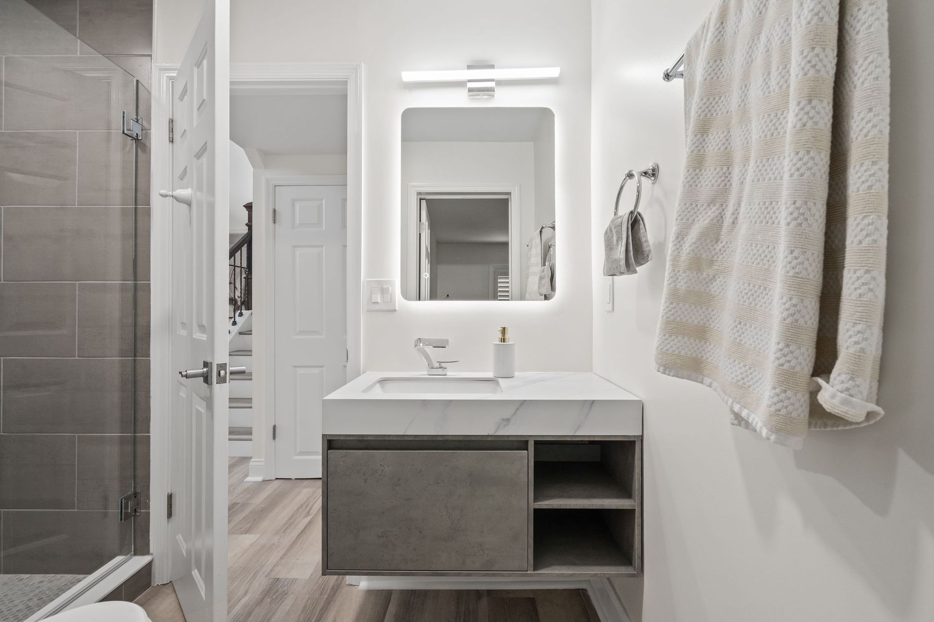 Modern white bathroom with vanity, mirror, towel, and tiled shower area