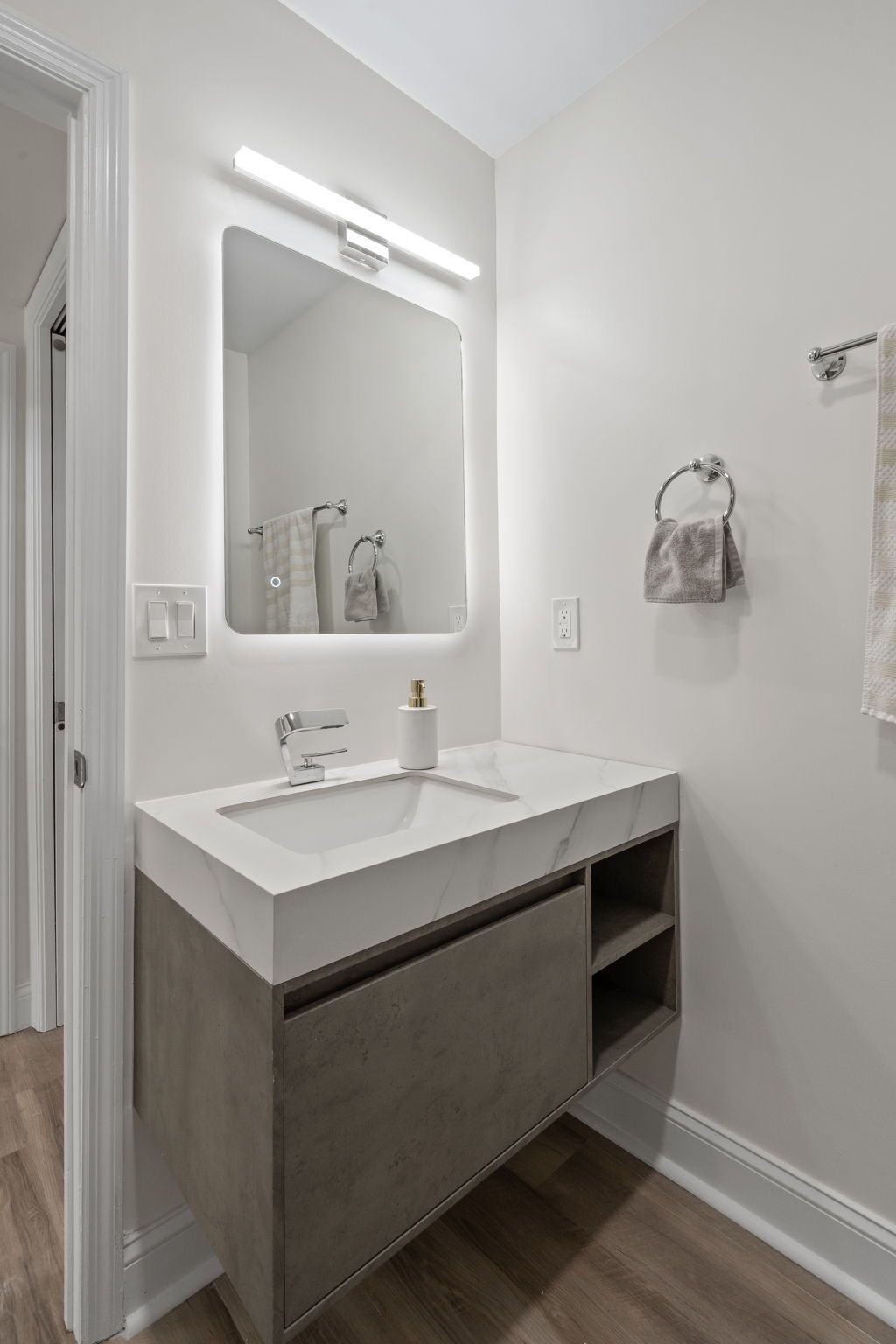 Modern bathroom vanity with white sink, large mirror, and wall light above.