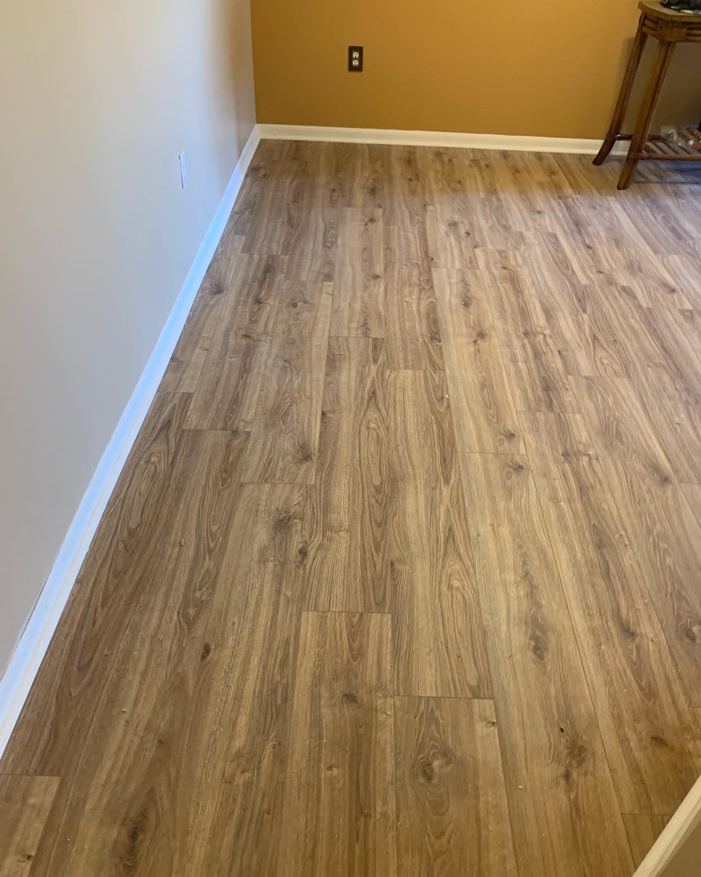 Empty room with light wood flooring, beige walls, and white baseboards.