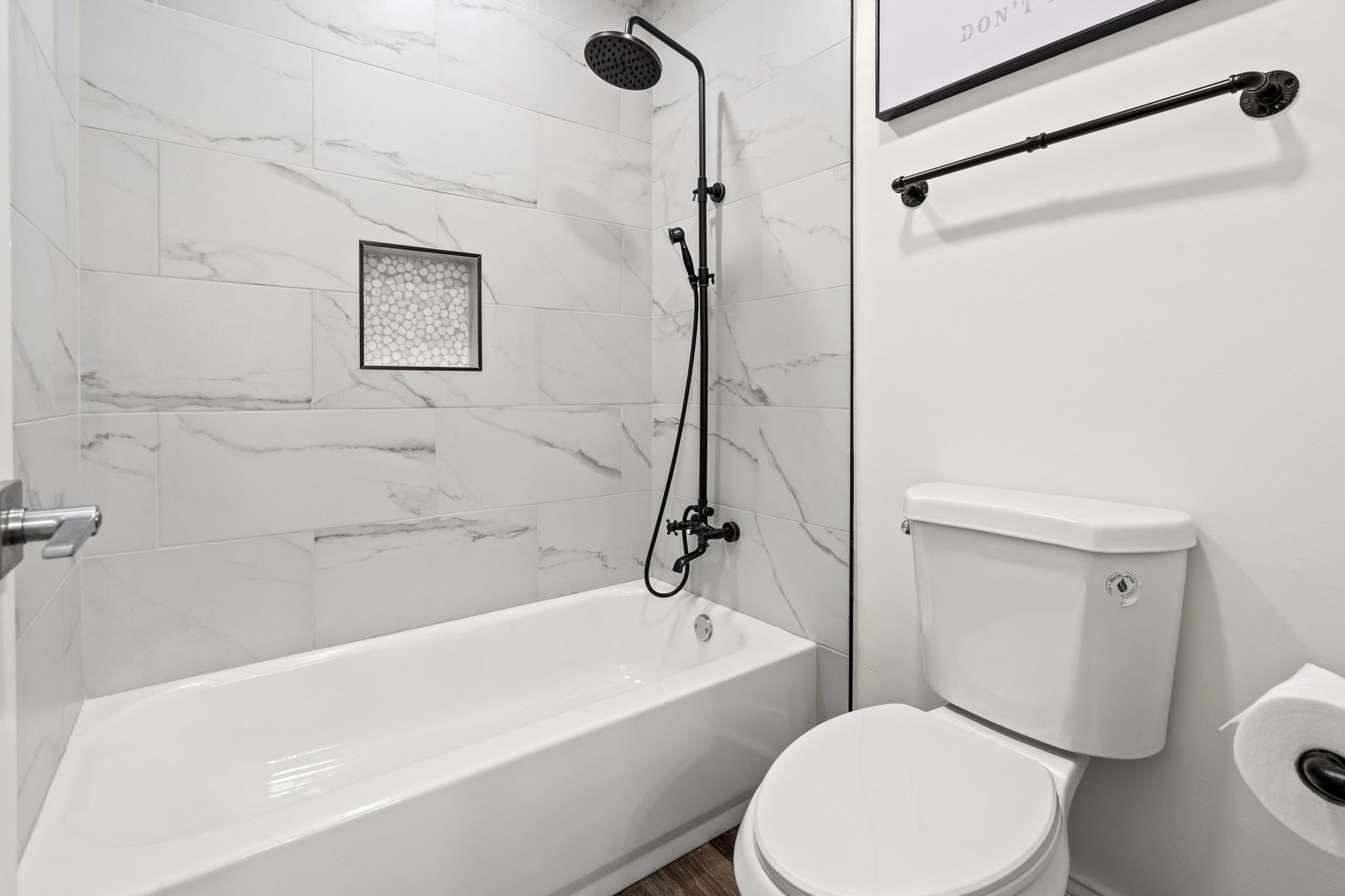Modern white bathroom with bathtub, showerhead, toilet, and tiled walls