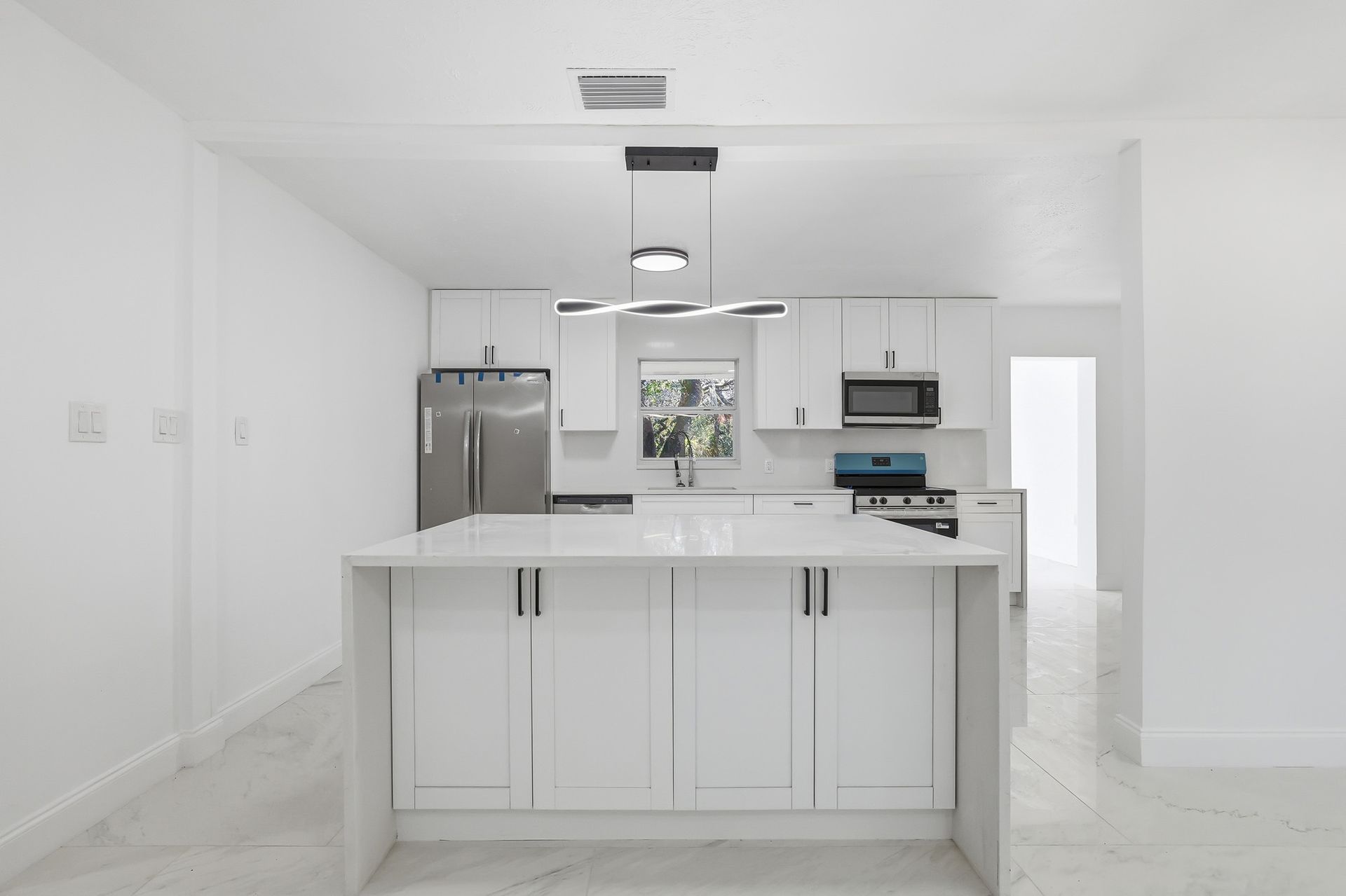 Bright white modern kitchen with island, stainless steel appliances, and gray tile floor