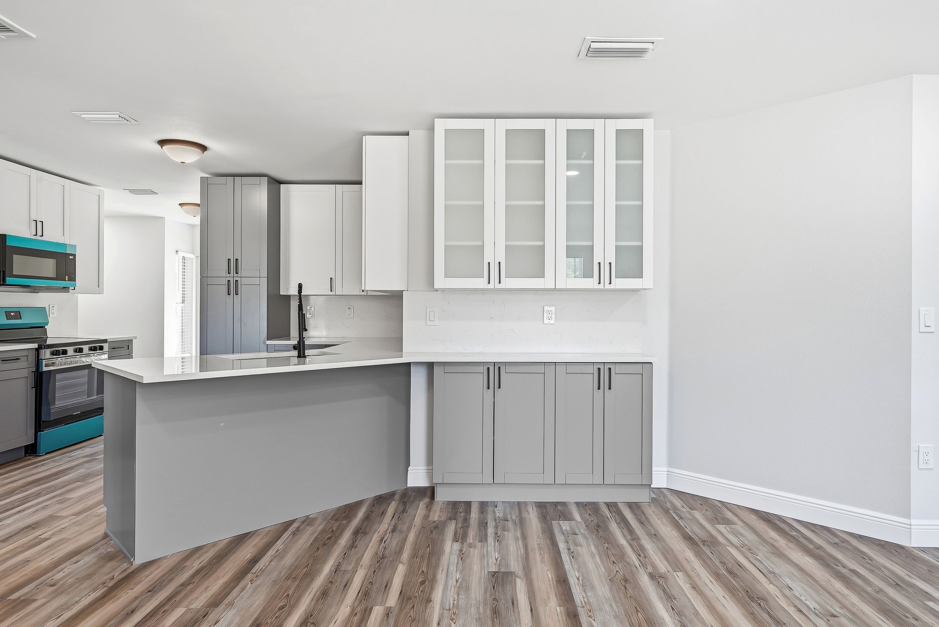 Two-tone gray kitchen with frosted glass-front upper cabinets and white quartz countertops