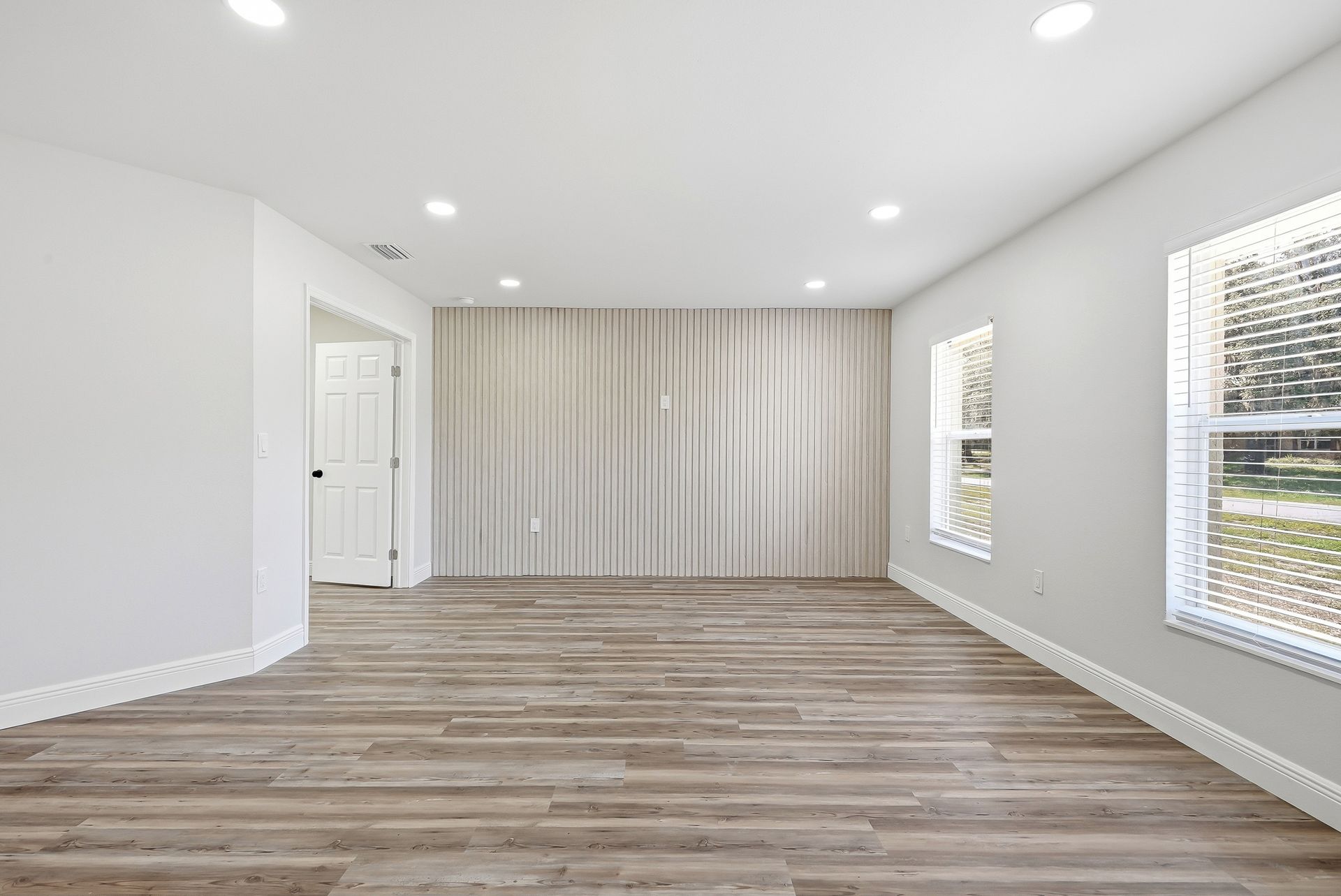 Bedroom or flex room with vertical wood slat accent wall and wood-look vinyl plank flooring