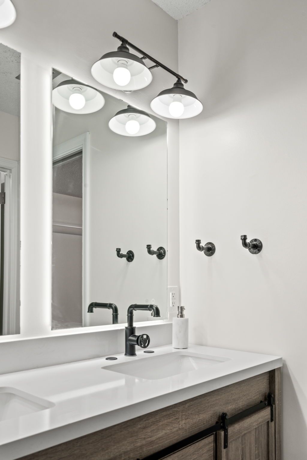 Bright bathroom vanity with mirror, white walls, black faucet, and three globe vanity lights