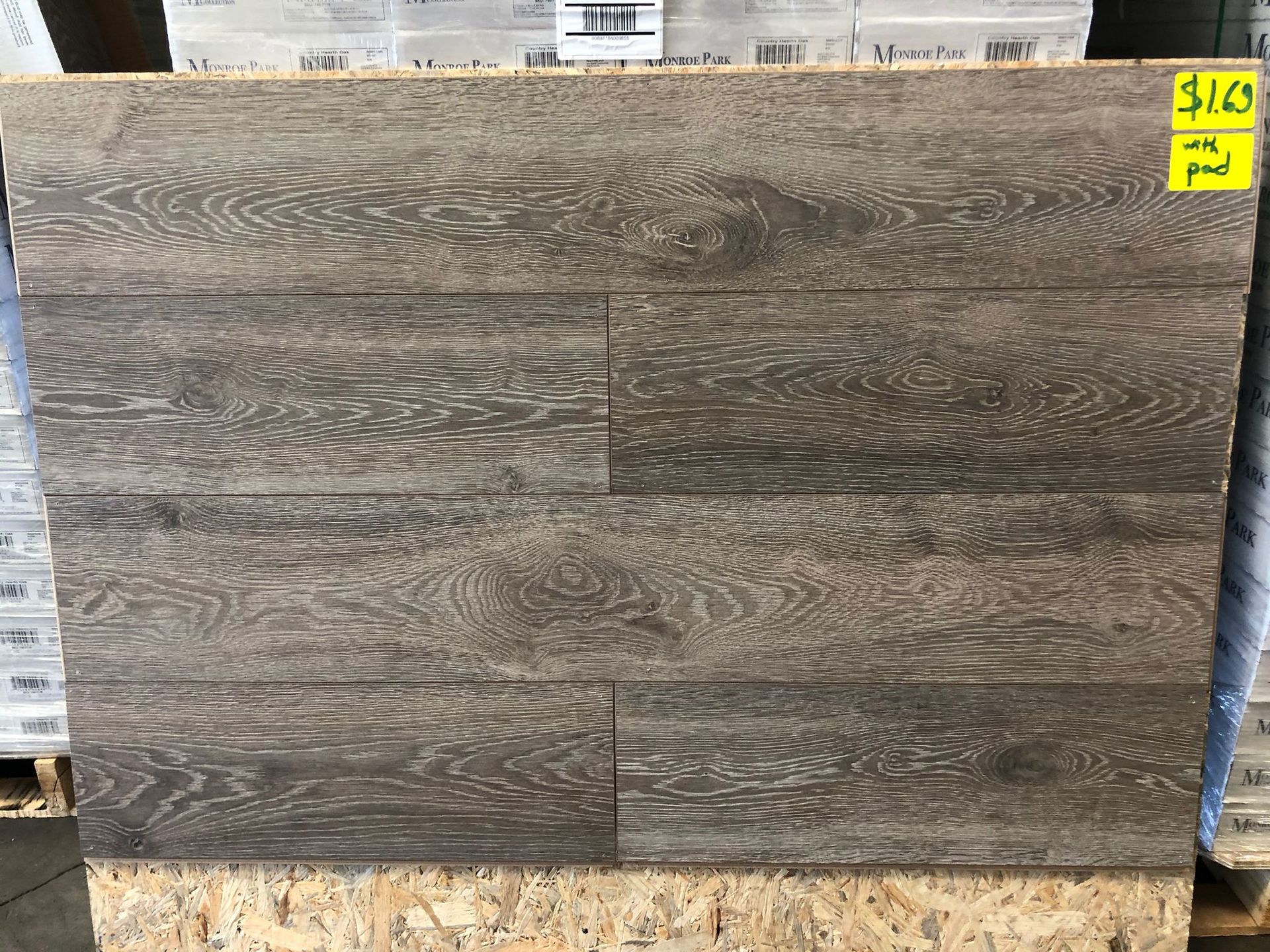 Dark wood-look tile or laminate sample board in a store display with a yellow price tag in the top right.