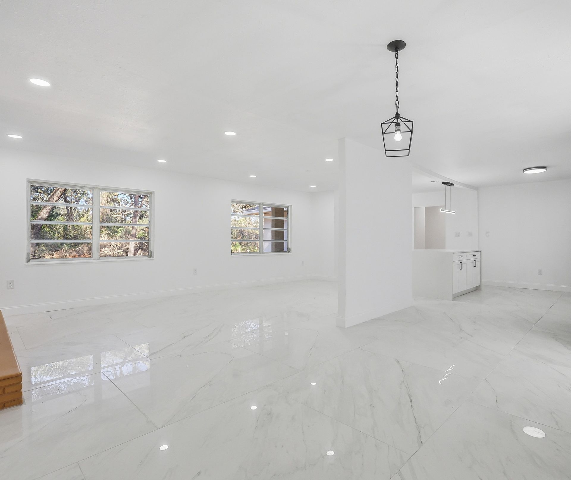 Bright empty white modern room with glossy floors, windows, and a hanging light fixture