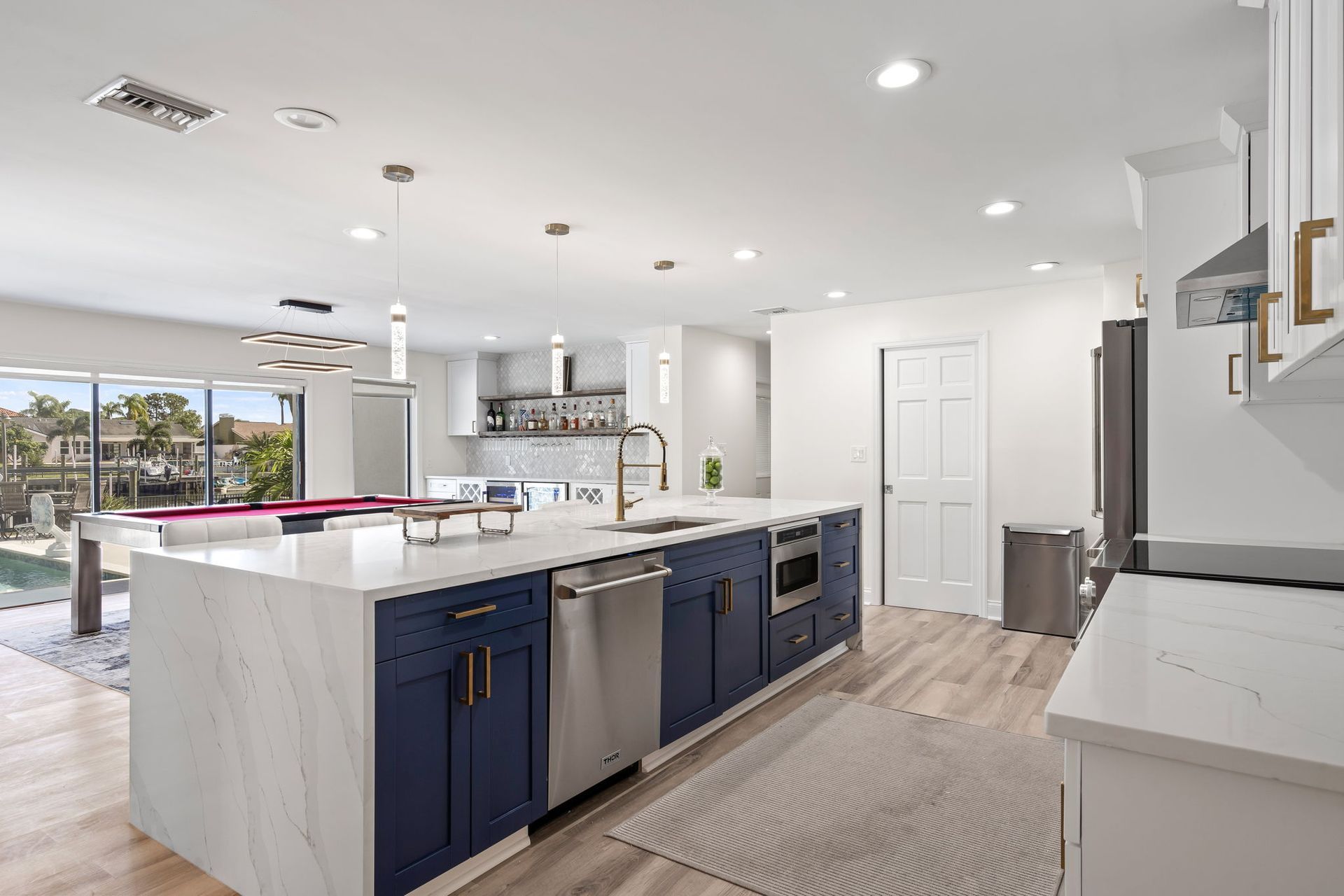 Bright modern kitchen with navy island, white cabinets, and large sliding glass doors to a patio