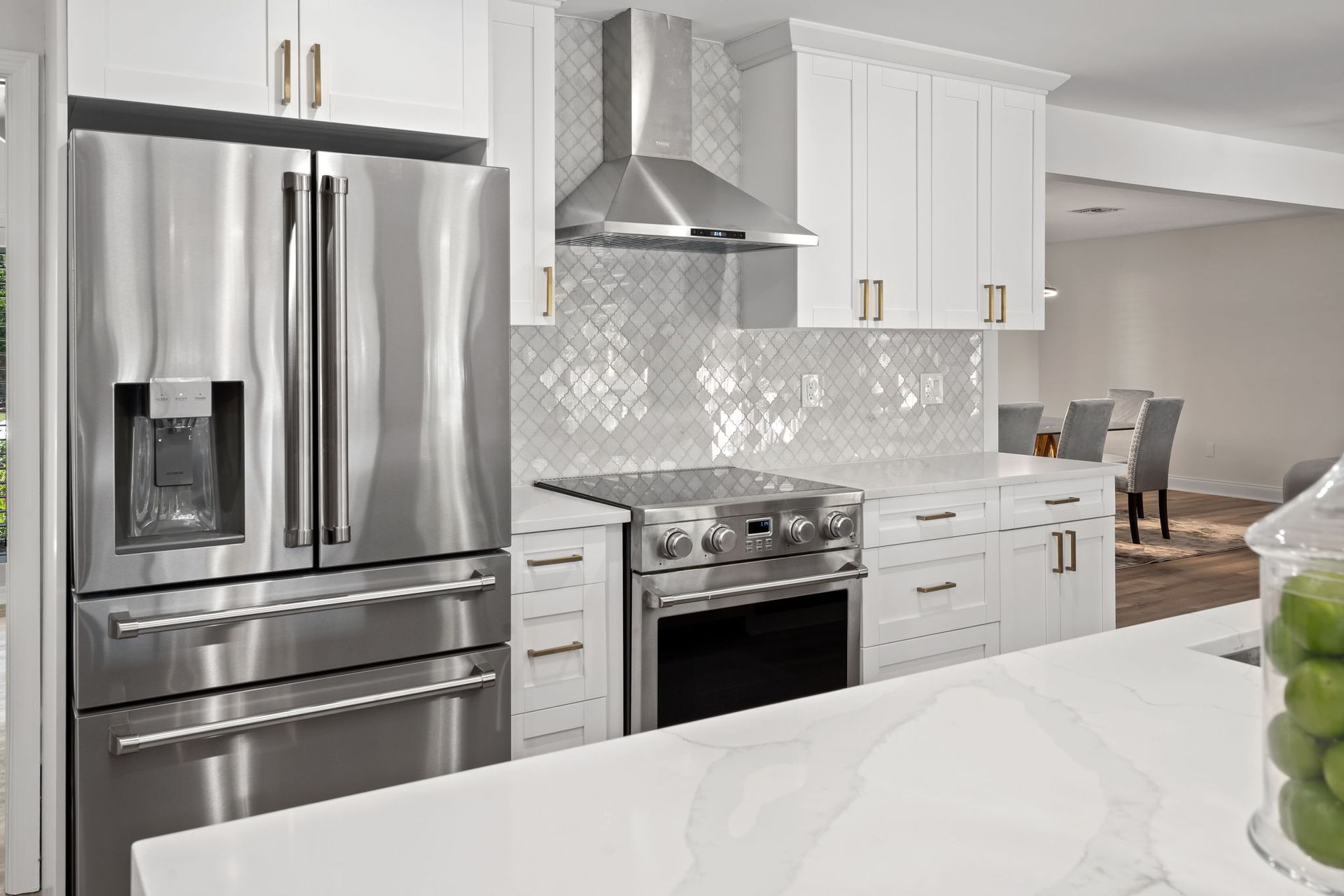 Bright modern kitchen with stainless steel appliances, white cabinets, and marble countertops