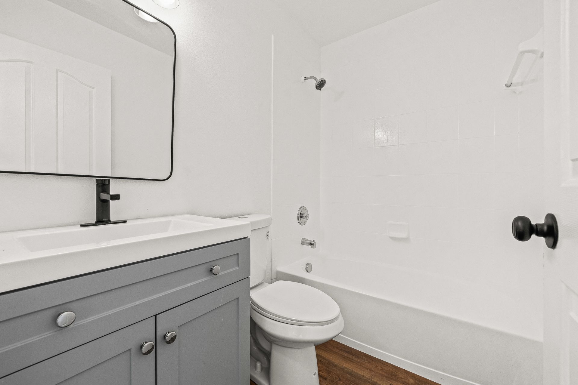 Small white bathroom with vanity, mirror, toilet, and bathtub