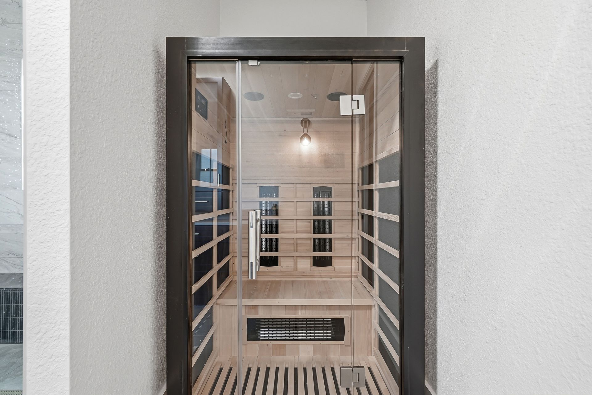 Built-in infrared sauna with wood paneling and glass door, part of a home spa bathroom remodel