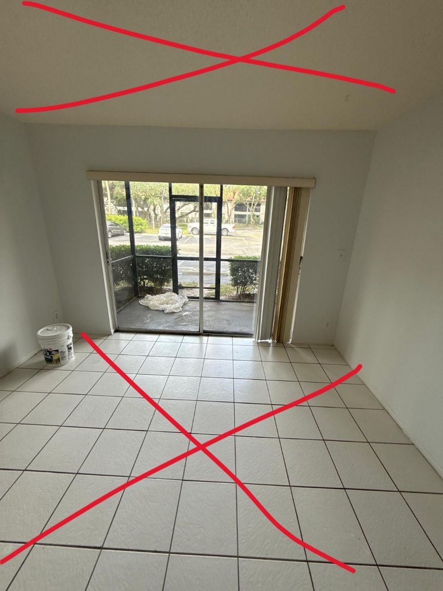 Empty white room with tiled floor, sliding glass doors, and a small item near the left wall.
