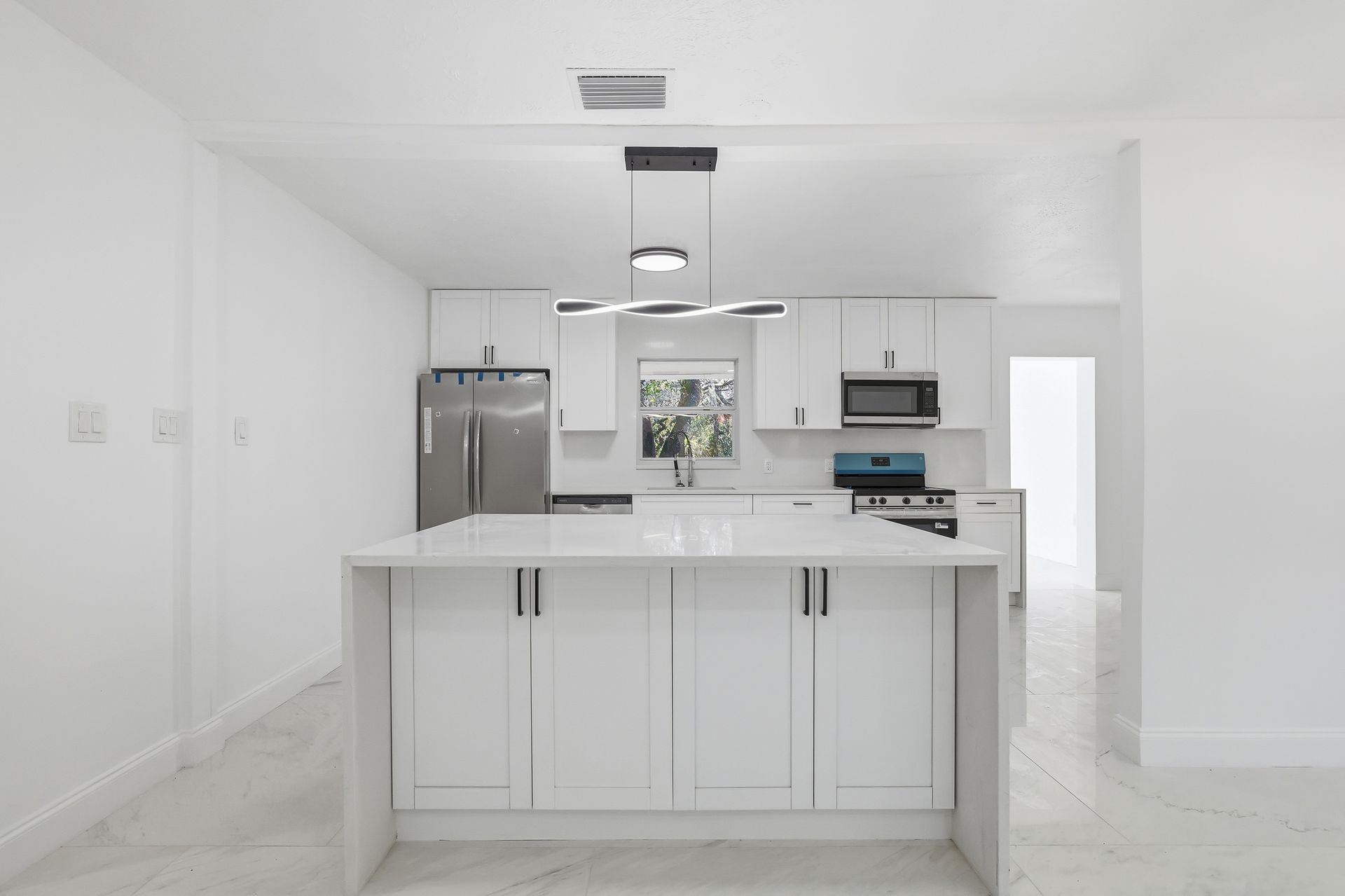 Bright white modern kitchen with an island, stainless steel appliances, and minimalist cabinets