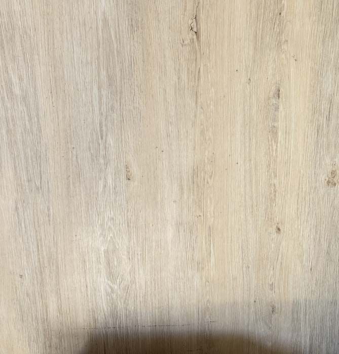 Light wood surface with subtle grain and a dark shadow along the bottom edge