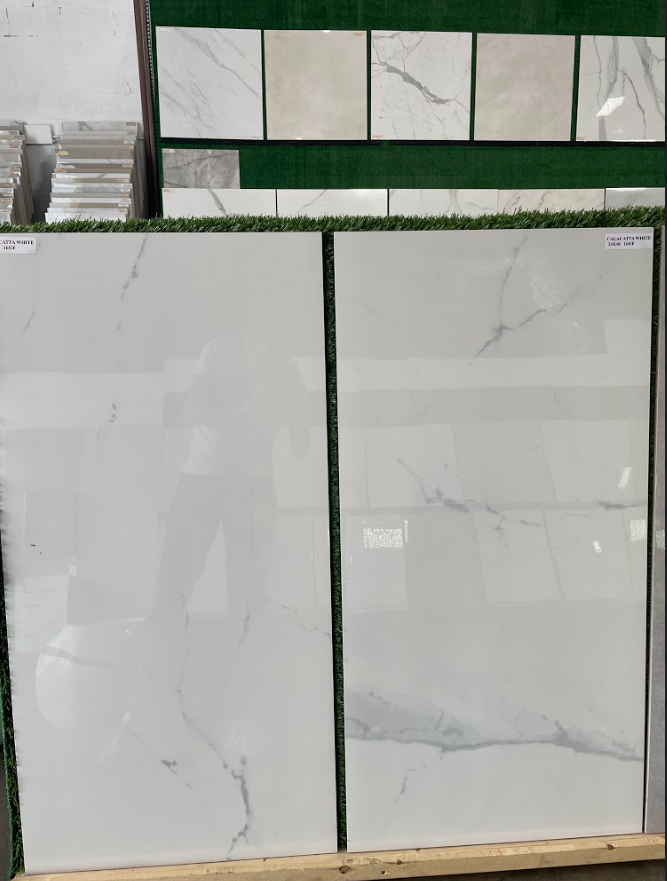 Two large white marble-look tiles displayed upright in a tile showroom.