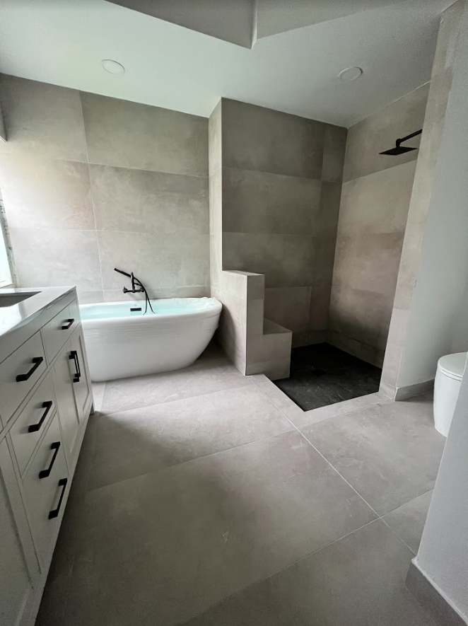Modern bathroom with freestanding tub, walk-in shower, vanity, and large gray tile flooring