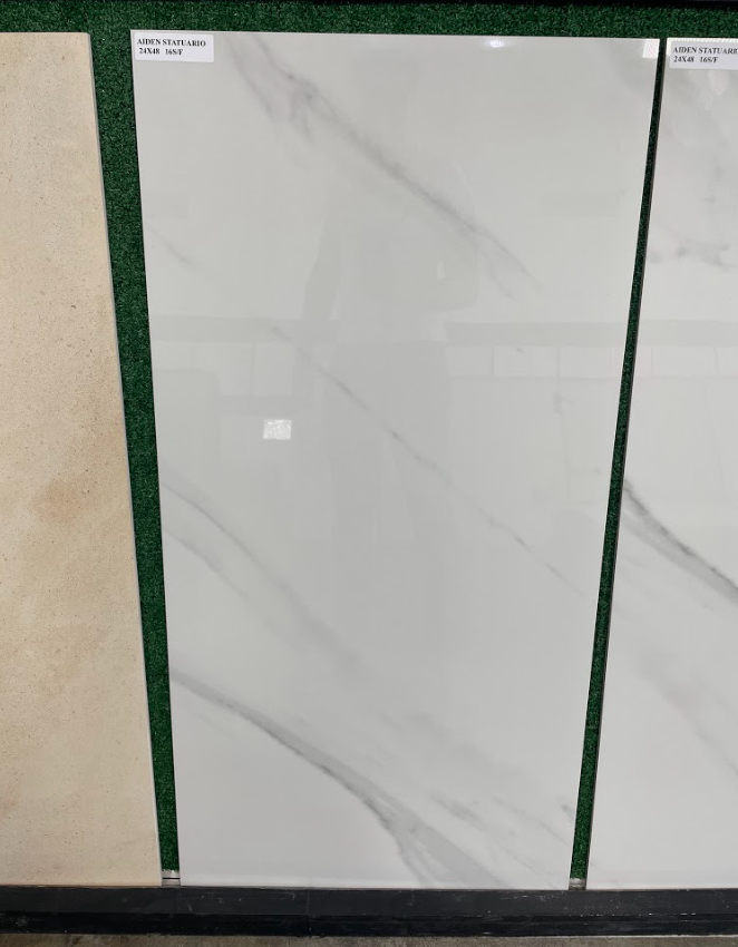 White marble-look tile samples displayed upright in a showroom, separated by green dividers.