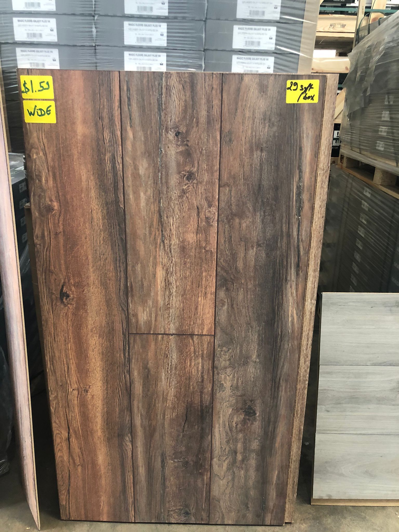 Display of large wood-look tile plank samples in a showroom, with brown weathered finish.