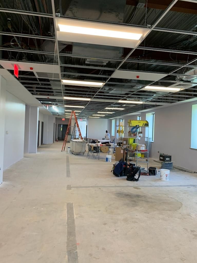 Empty office under renovation with exposed ceiling, ladder, and construction materials