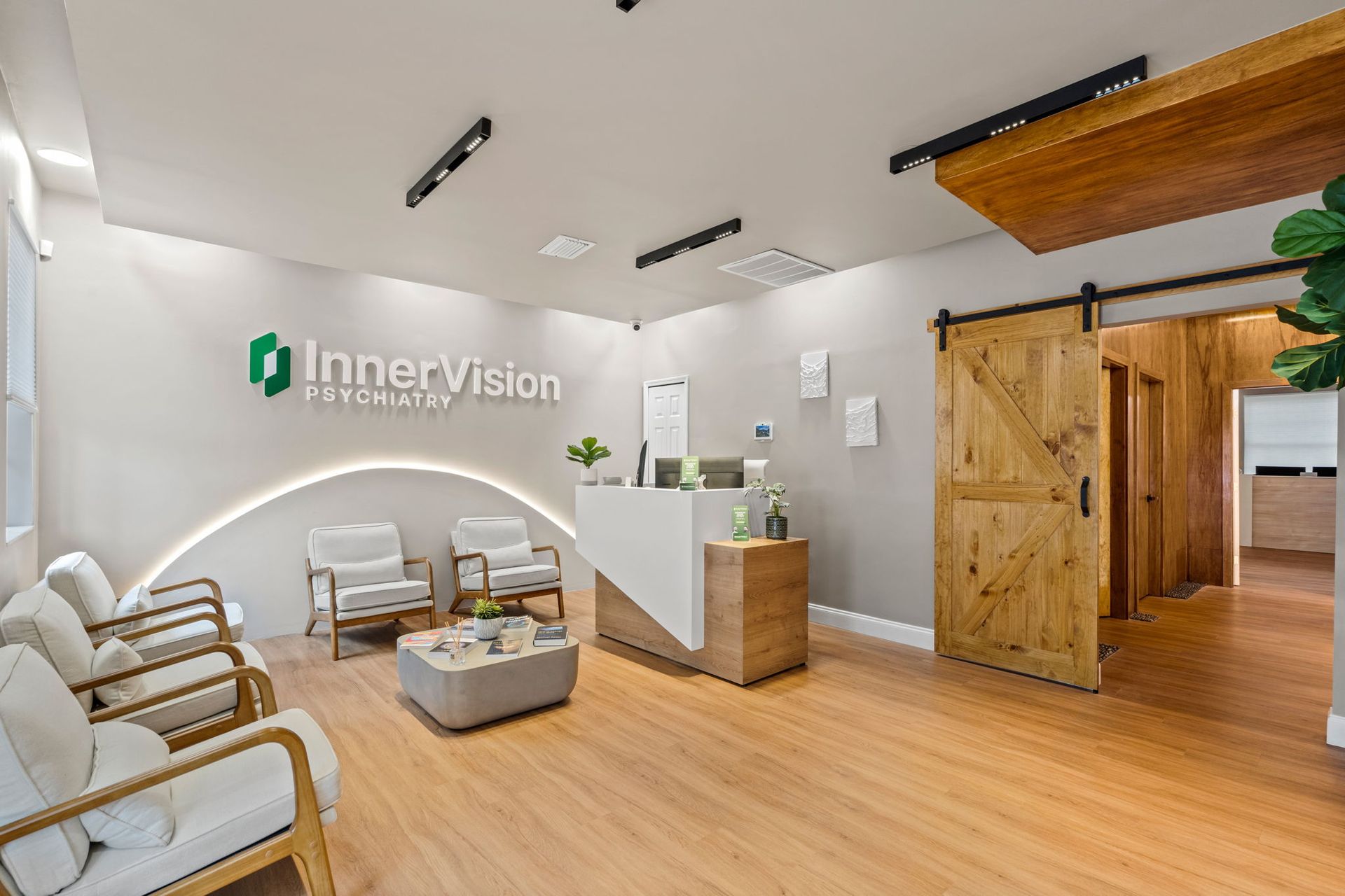 Modern clinic waiting room with white chairs, wood floors, and reception desk under InnerVision sign