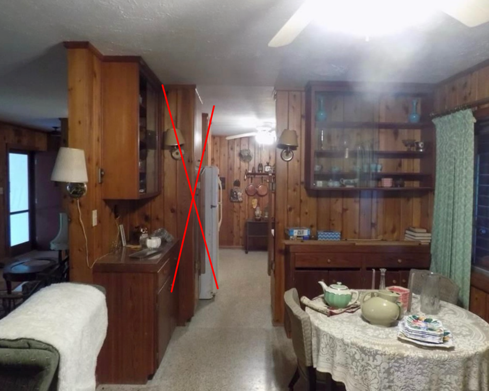 Wood-paneled kitchen and dining room with cabinets, table, and doorway down the hall