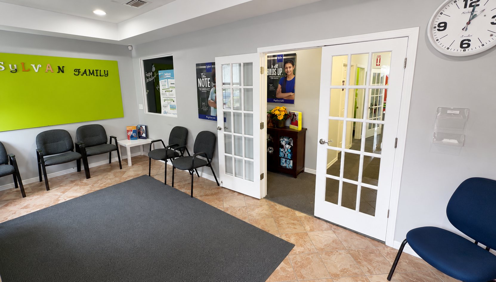 Bright waiting room with chairs, green wall, glass double doors, and a wall clock.