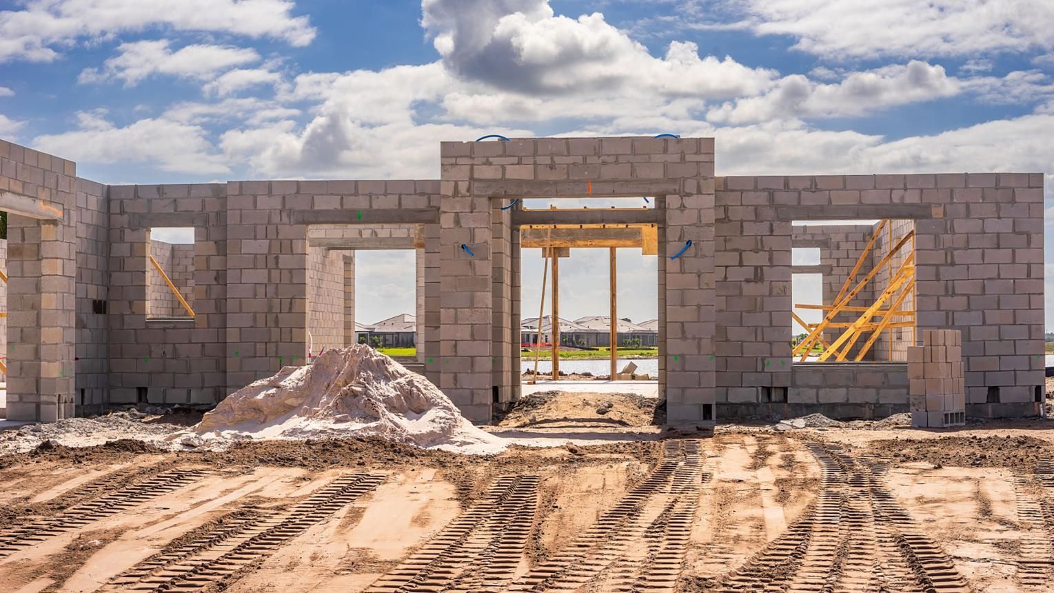 Unfinished cinder block building under construction with dirt foreground and wooden scaffolding inside.