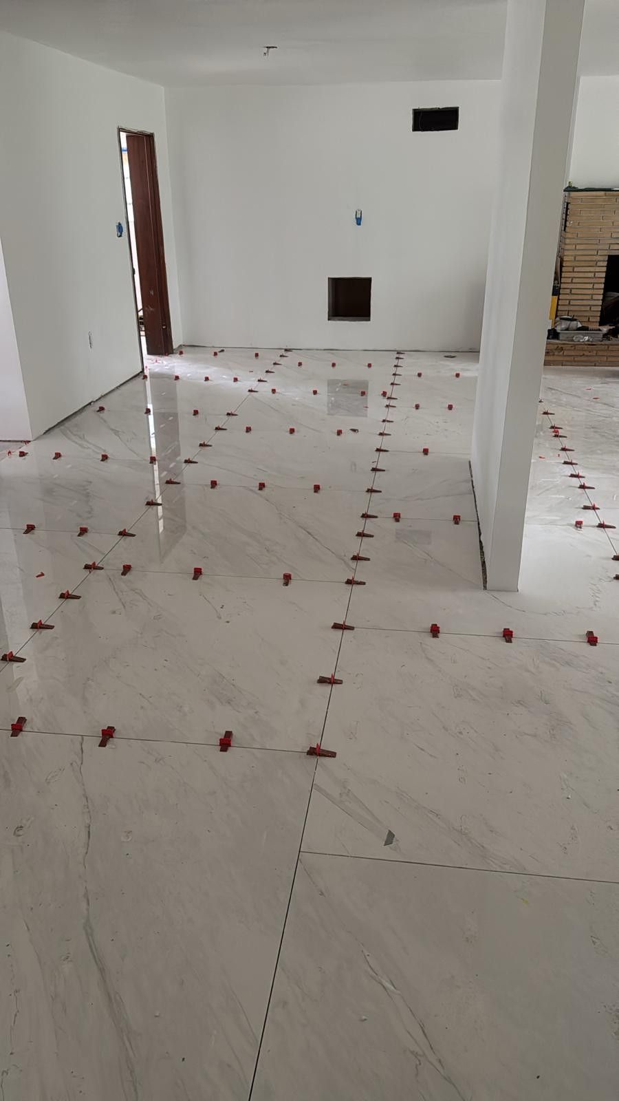 Empty white tiled room with scattered red markers on the floor and open doorways.