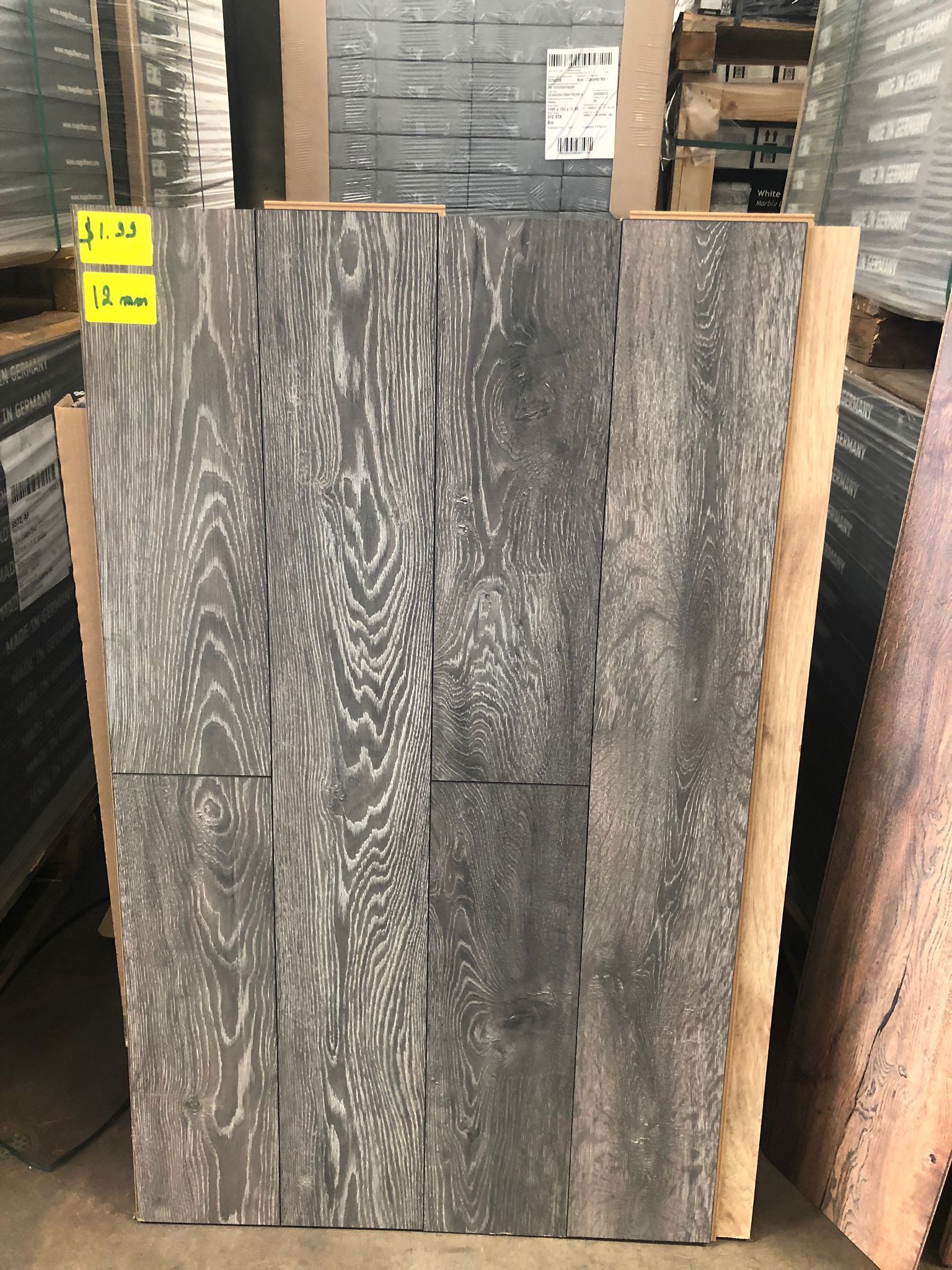 Stacked gray wood planks with visible grain patterns in a lumberyard setting