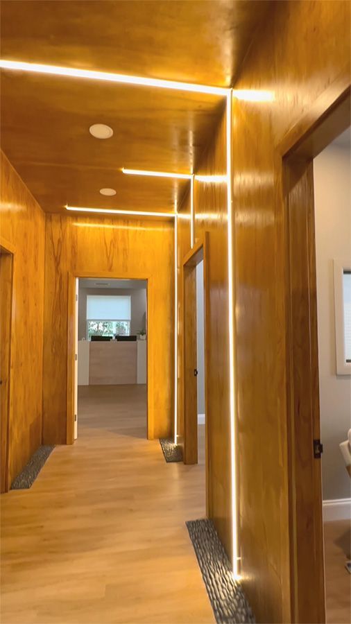 Wood-paneled hallway with recessed lights and a doorway leading to a bright room.