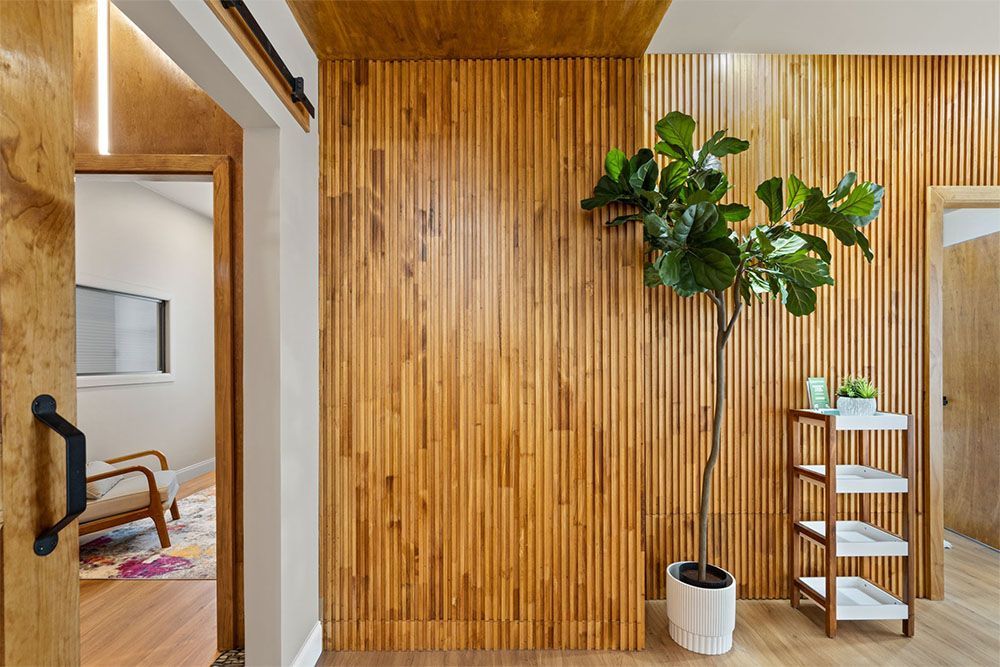 Modern interior with wood slat wall, potted tree, and white shelf in a bright hallway