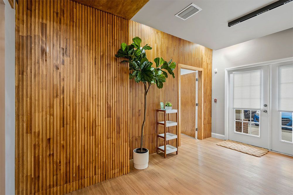Bright wood-paneled hallway with a potted plant, shelf, and glass doors leading outside