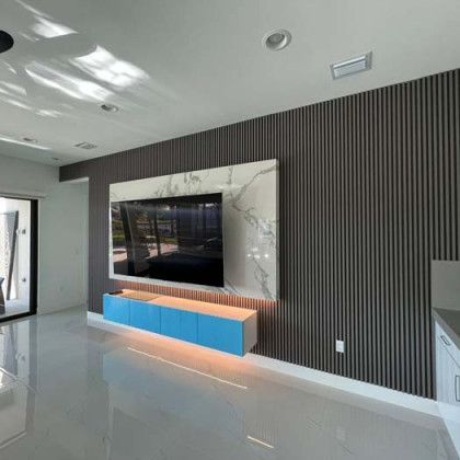 Modern living room with striped accent wall, wall-mounted TV, and blue-orange media console on glossy floor