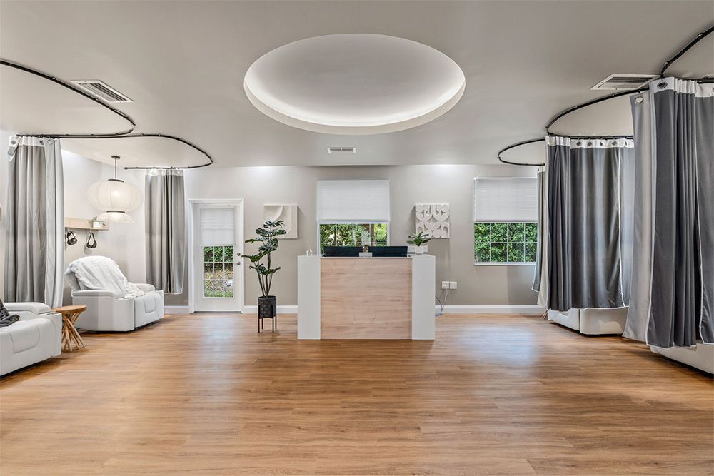 Modern spa studio with wood floors, curtained treatment bays, and a central reception desk