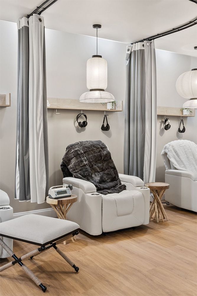 Modern spa room with reclining chair, pendant lamp, curtains, and wooden floor