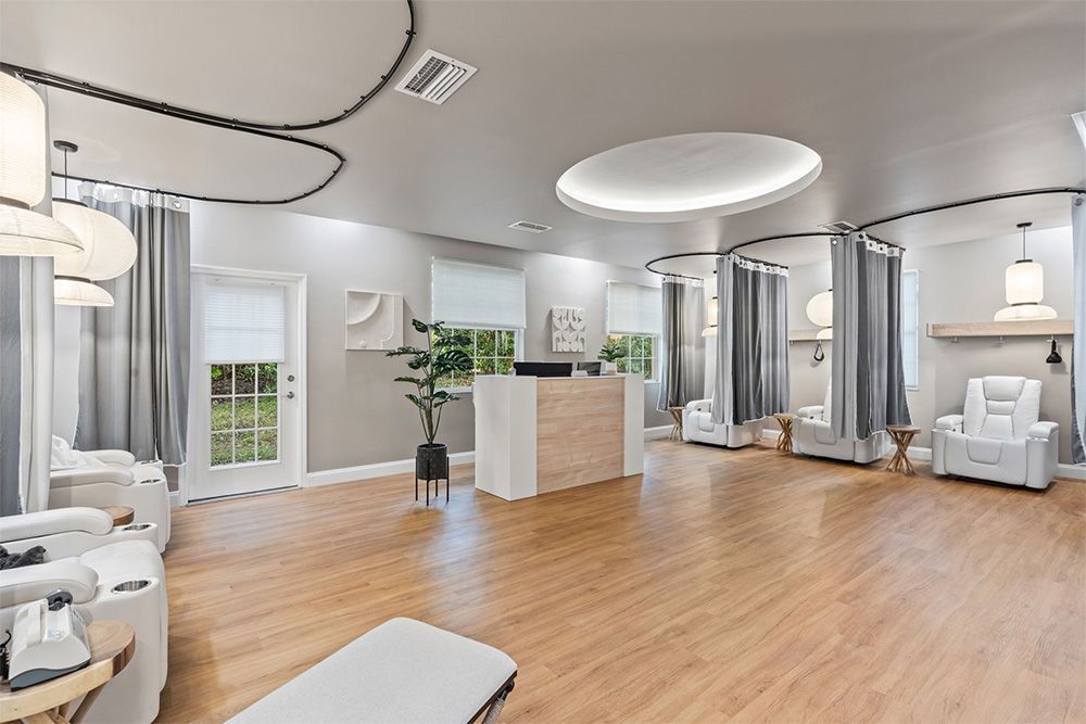 Bright modern spa reception with white chairs, wood floors, and soft circular ceiling lights