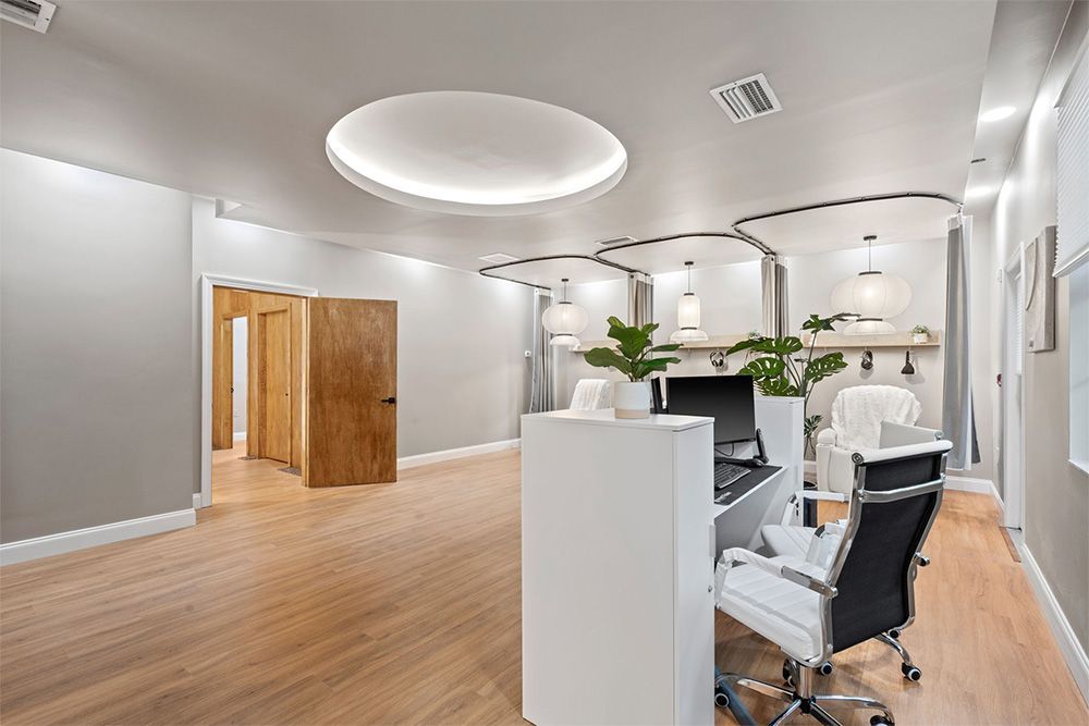Modern dental office with white chairs, wooden floors, and curved ceiling lights