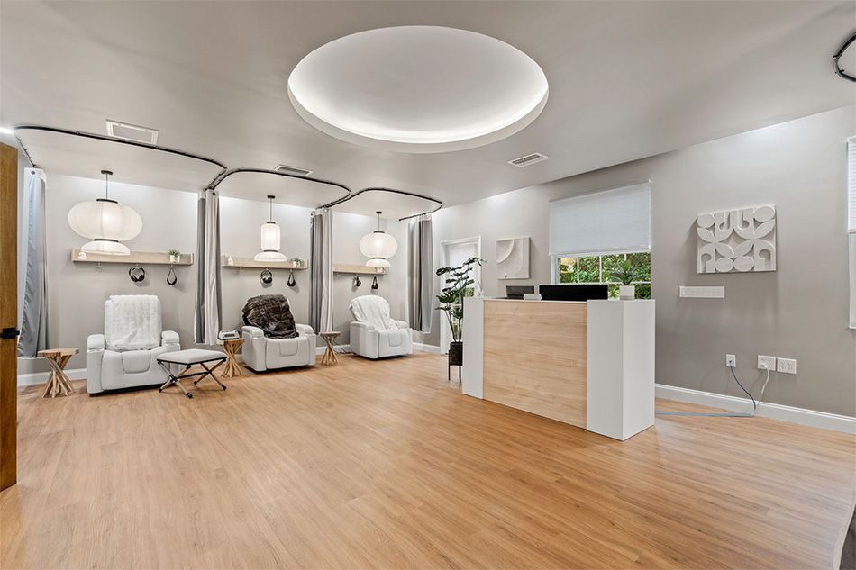 Modern spa reception with white seating, wood floors, arched treatment rooms, and a pale wood front desk