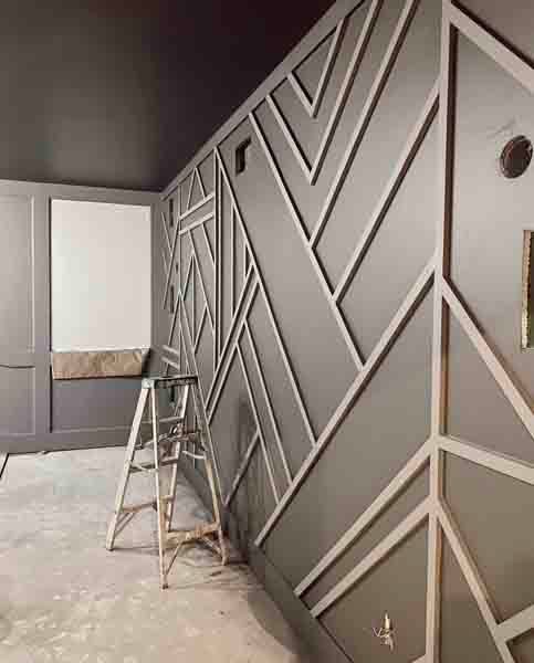 Gray room with geometric wall mural and a small step ladder on a dusty floor