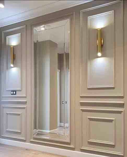 Elegant hallway with a large wall mirror and brass sconces on paneled cream walls