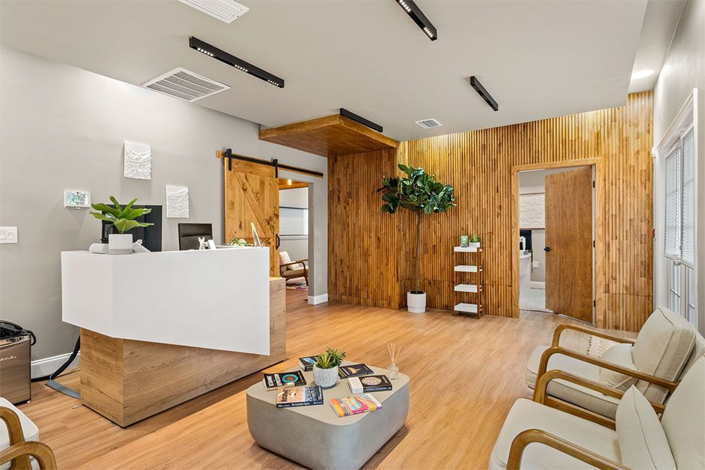 Modern office lobby with white reception desk, wood accents, and lounge chairs