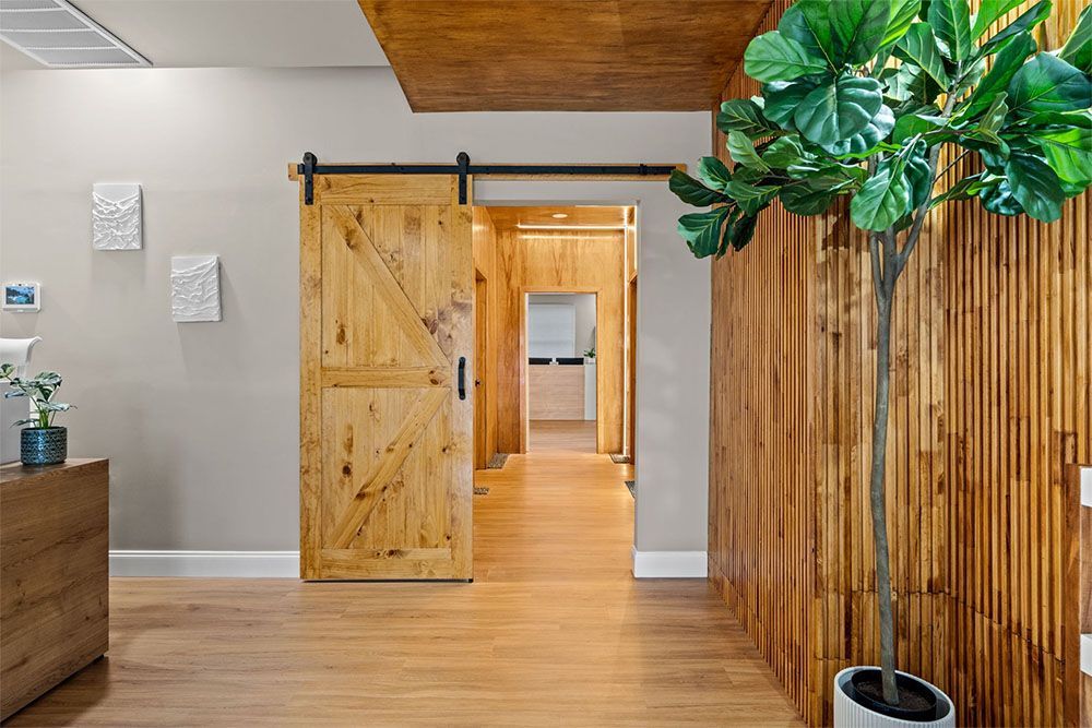 Modern interior with open wooden sliding door, light wood floors, and a potted plant near a wood slat wall