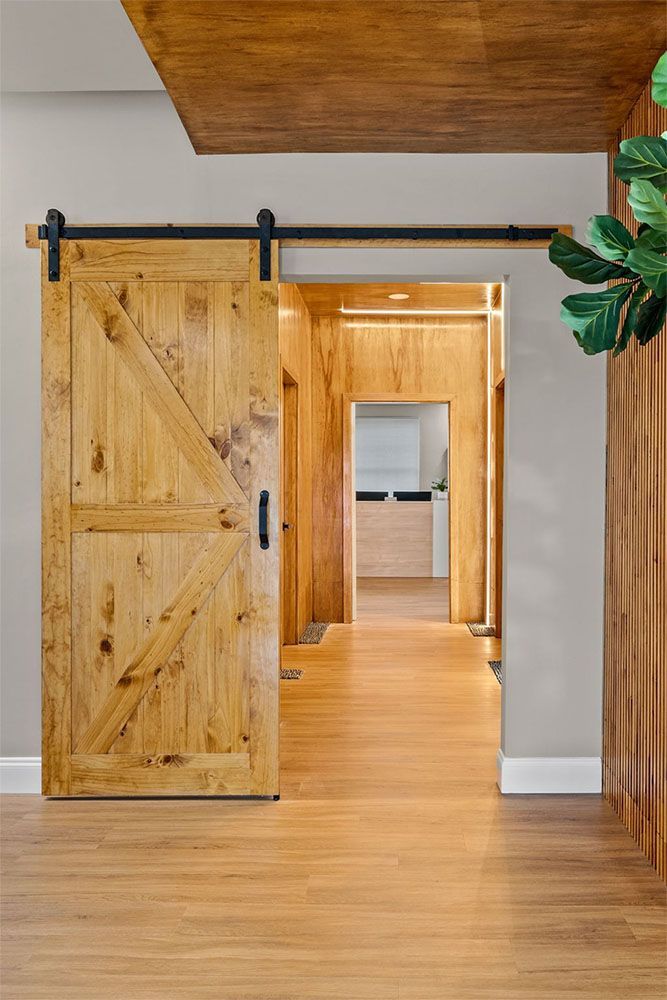 Wooden barn door open to a warm hallway with hardwood floors and white walls