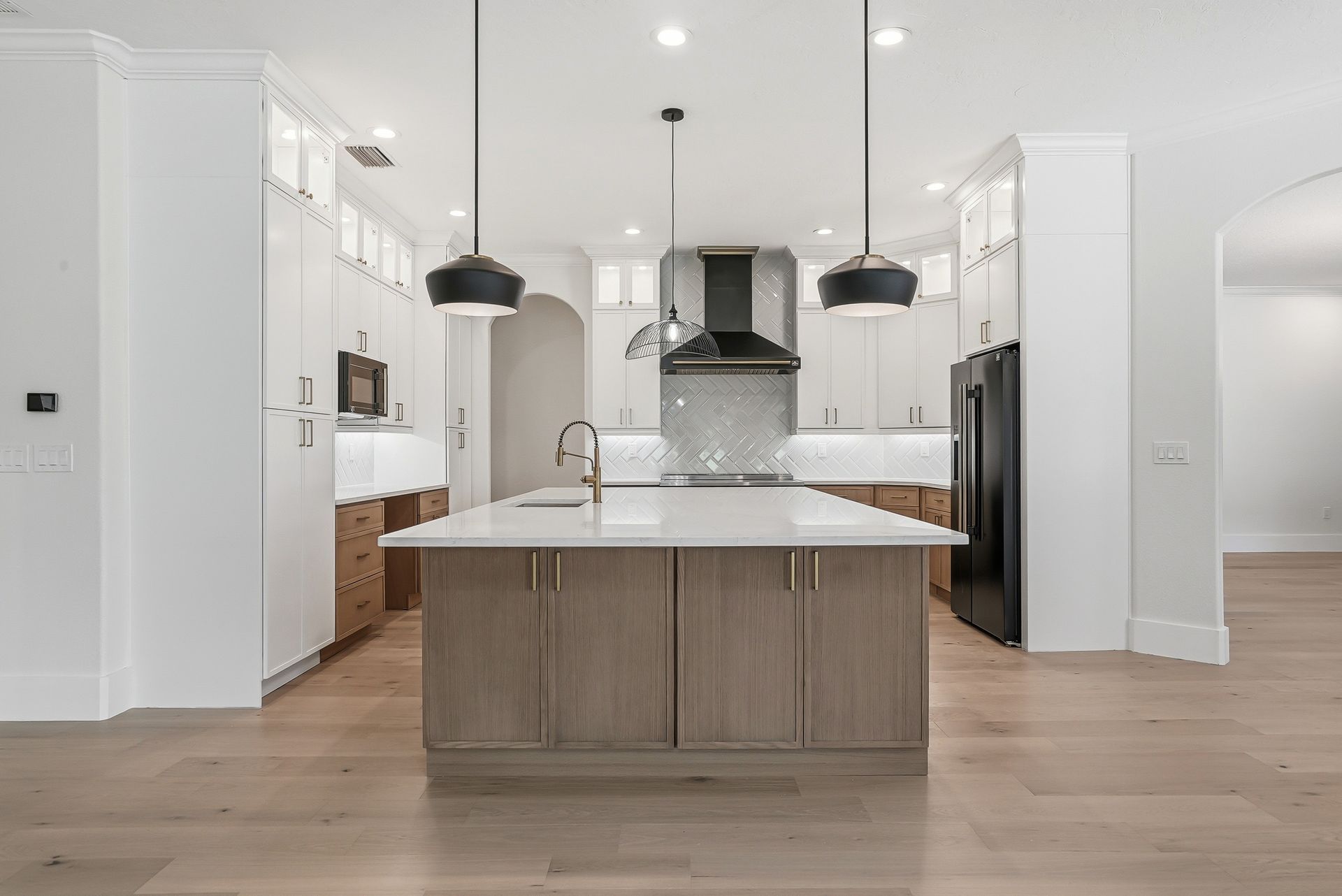Open-concept kitchen with light wood island, white quartz countertops, glass-front cabinetry, and black pendant lighting